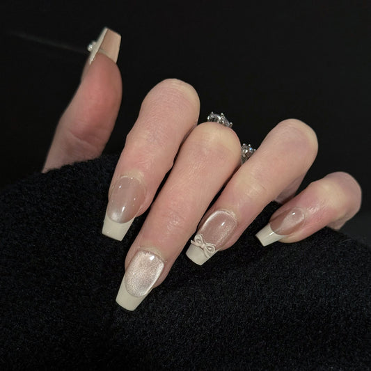 Ballerina French Tip Cat Eye Press-On Nails – Nude Base with 3D White Bow Charms, Worn on Hand