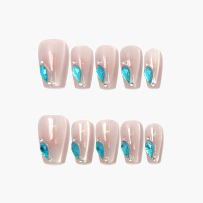 Aqua Drop press-on nails featuring a sheer nude cat-eye base with a precise line of teardrop-shaped aqua gemstones along the edge, shimmering with cool blue contrast.
"